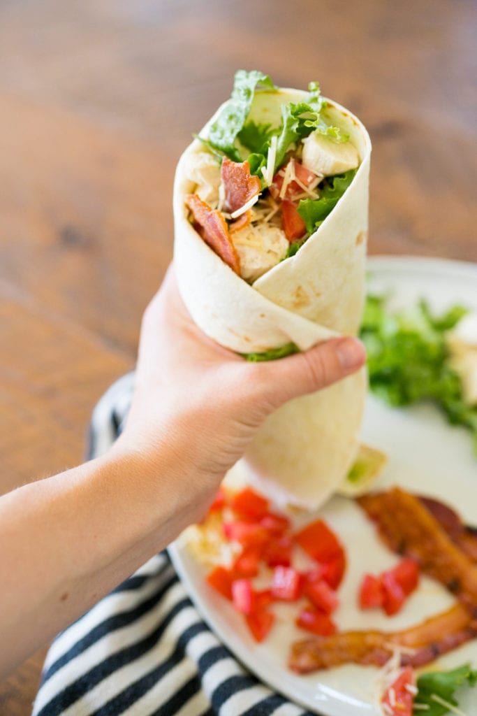 chicken wrap, a hand holding the chicken wrap before eating.