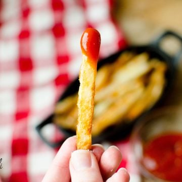 Crispy oven baked french fry dipped in ketchup
