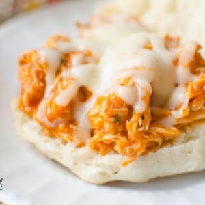 Shredded chicken mixed with red marinara sauce on top of a bun with melted mozzarella cheese.