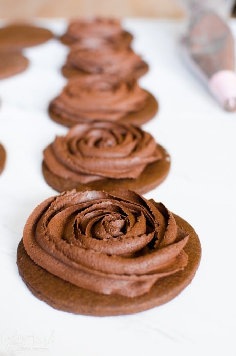 Chocolate cut-out cookies are frosted with a rose on top to make it super fancy.