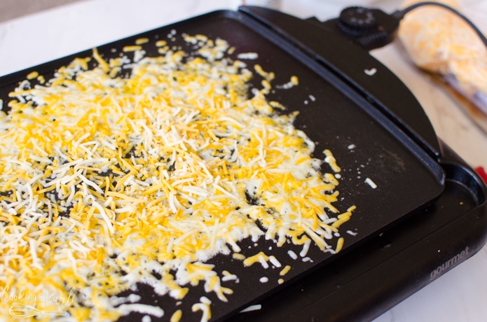 Shredded cheese sprinkled directly onto the griddle.