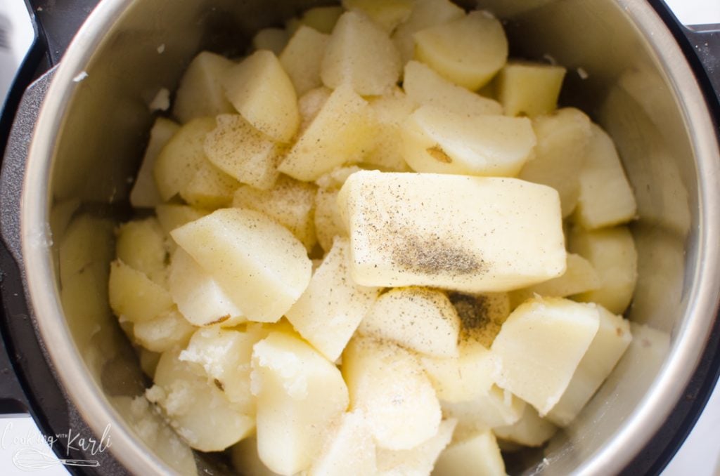 cooked potatoes with butter and seasonings in the Instant Pot in the process of making Instant Pot mashed potatoes