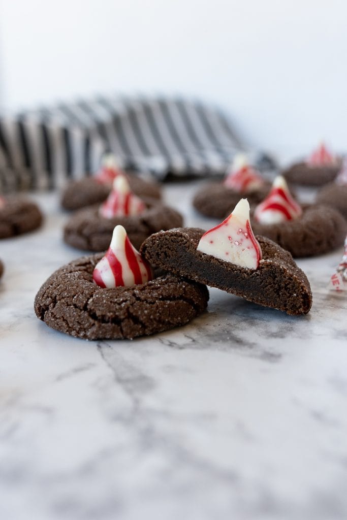 chocolate peppermint kiss cookies on the counter, one cut in half.