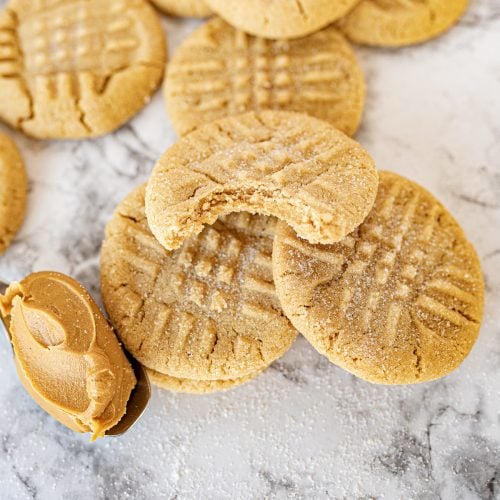 peanut butter cookies on the counter next to a spoonful of peanut butter.