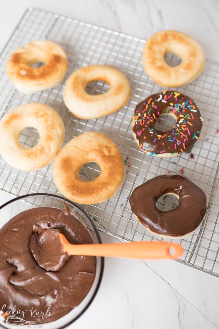 donuts being iced with chocolate frosting
