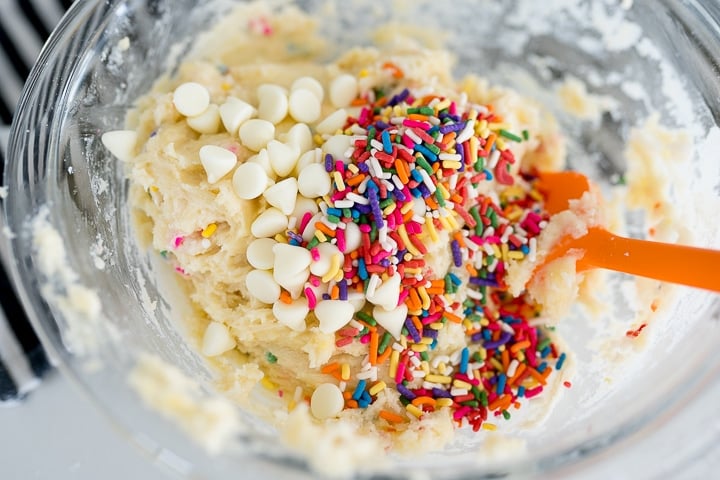 sprinkles and white chocolate chips being mixed into the brownie batter