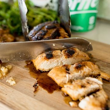 Grilled chicken marinated in sprite and soy sauce, being cut up.