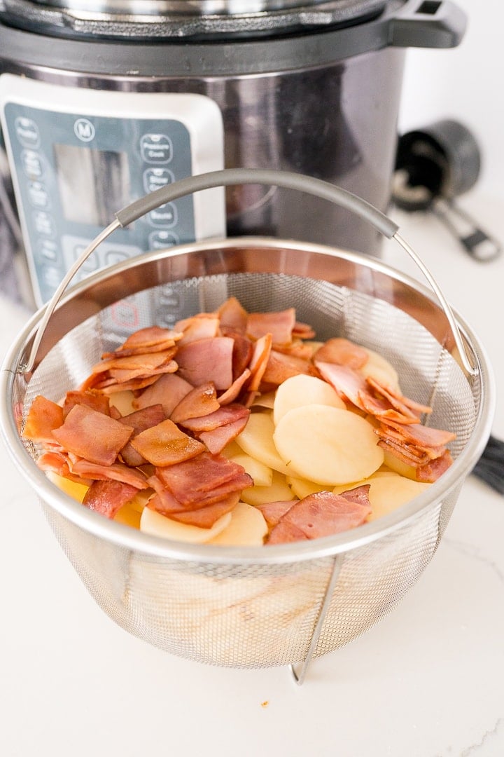 sliced potatoes and cut ham in a steamer basket