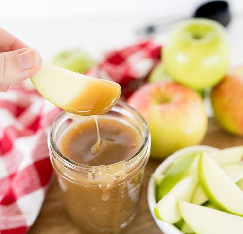 apple being dipped into the caramel sauce