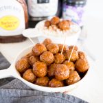 Grape jelly meatballs in a large plate/bowl with bbq sauce and grape jelly in the background