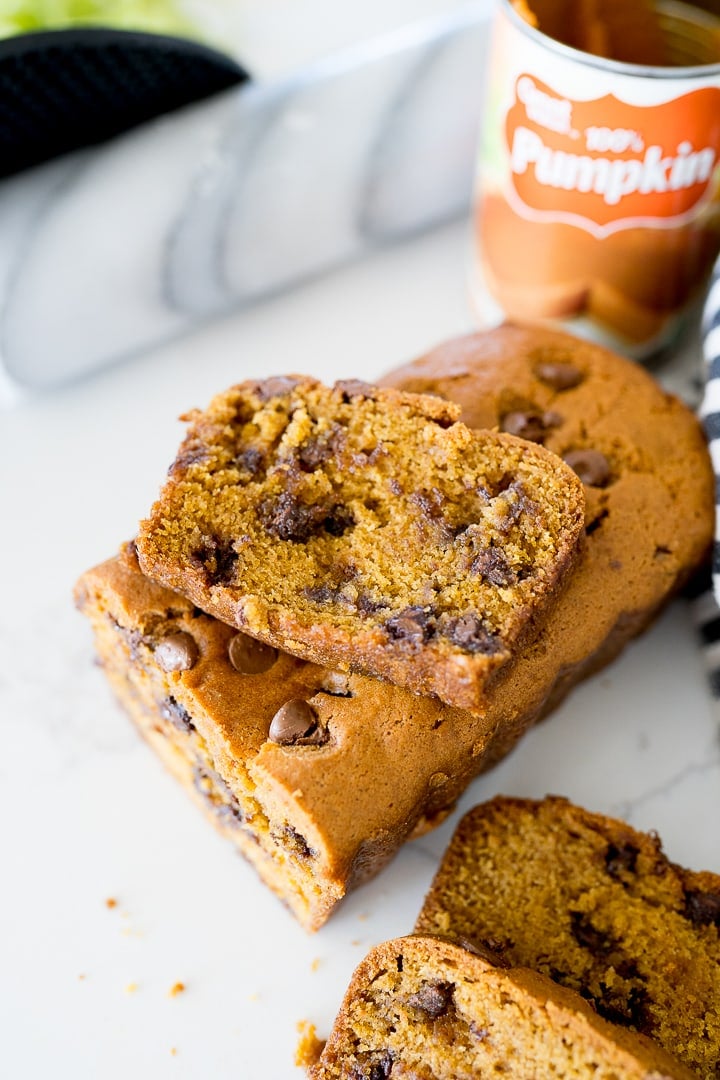 A slice of pumpkin chocolate chip bread on top of the uncut loaf.