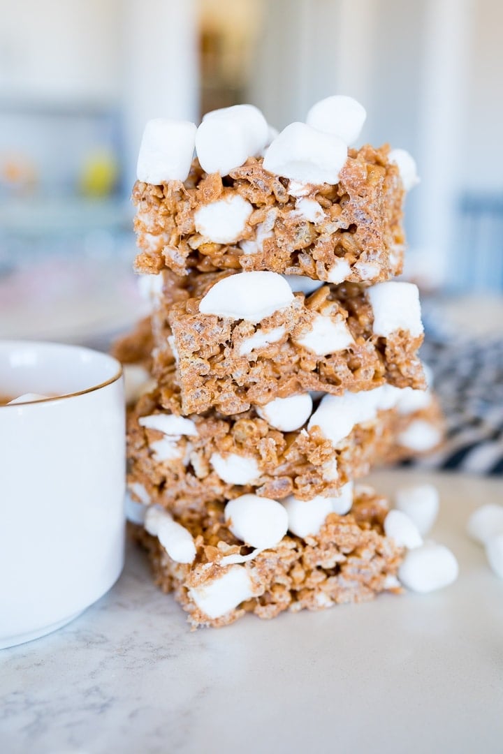 Rice Krispies that are hot chocolate flavored stacked on top of each other next to a cup of cocoa