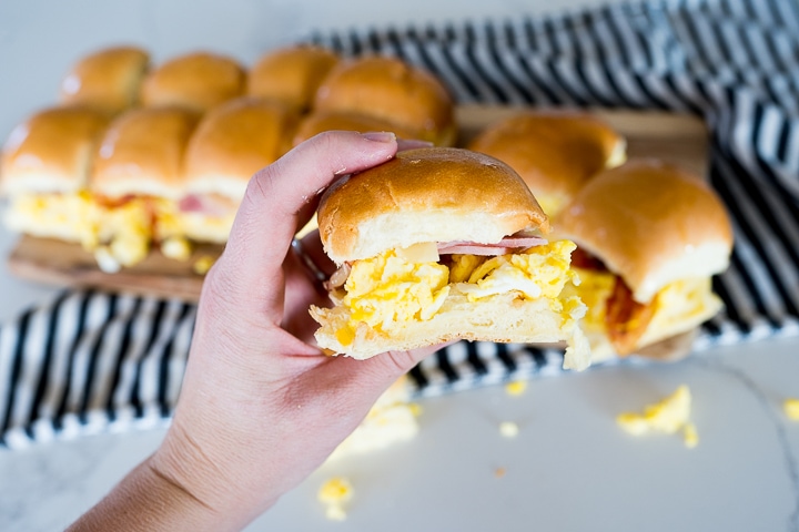 breakfast sandwich being held with ham, eggs and cheese