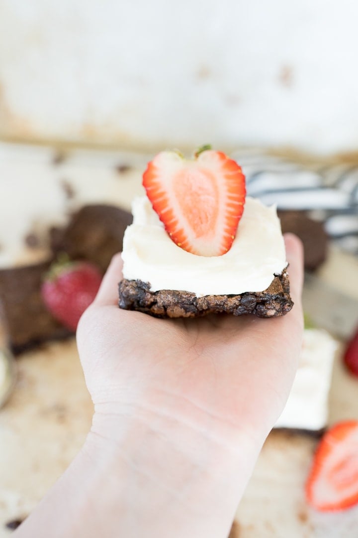 brownies cut with white cream cheese frosting and strawberries