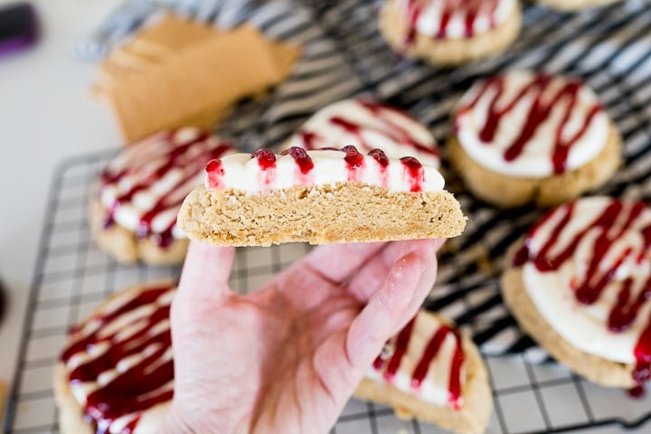 graham cracker cookies with cream cheese frosting and raspberry drizzle cut in half