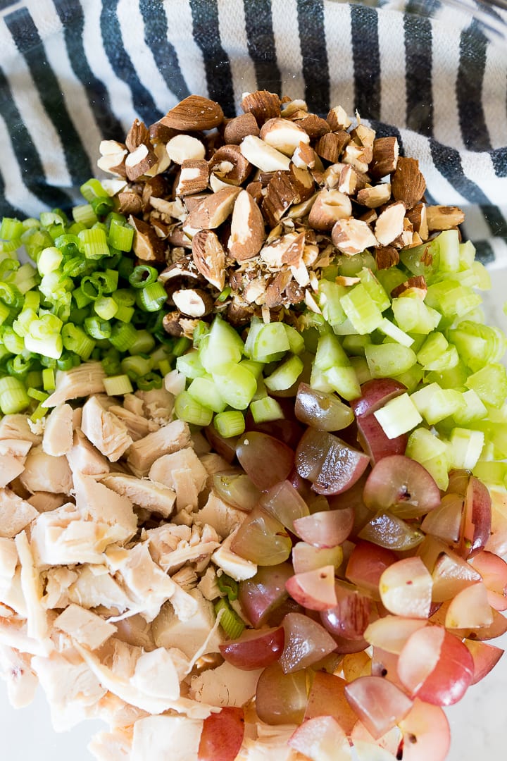 cubed chicken, chopped grapes, green onion, celery and almonds in a bowl.