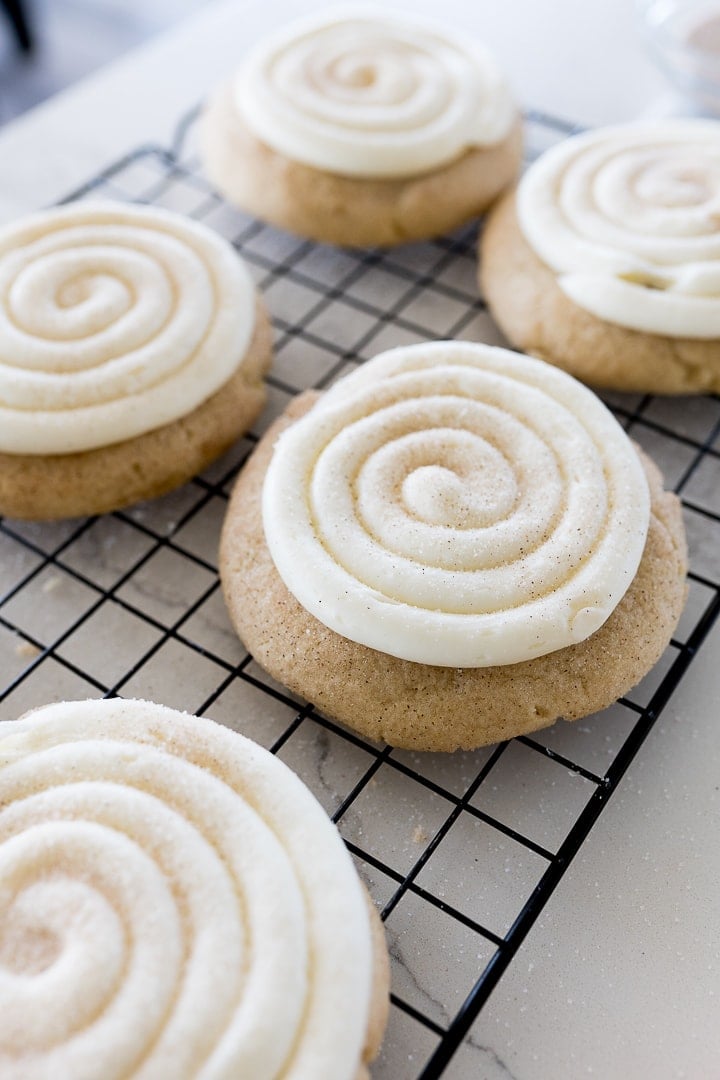 snickerdoodle cupcake cookies on a cooling rack with swirled frosting and cinnamon and sugar
