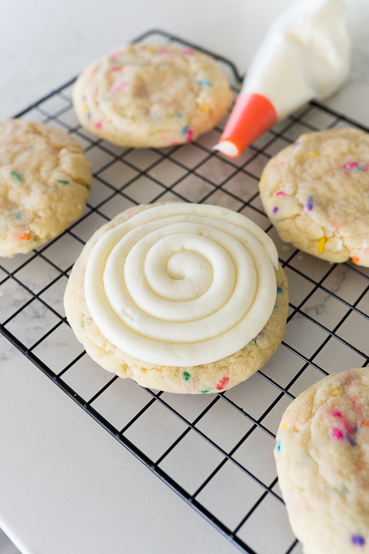 cake batter cookies with swirled cream cheese frosting on a cooling rack