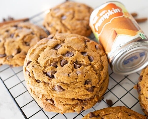 Crumbl pumpkin chocolate chip cookies on a cookie cooling rack with a can of pumpkin
