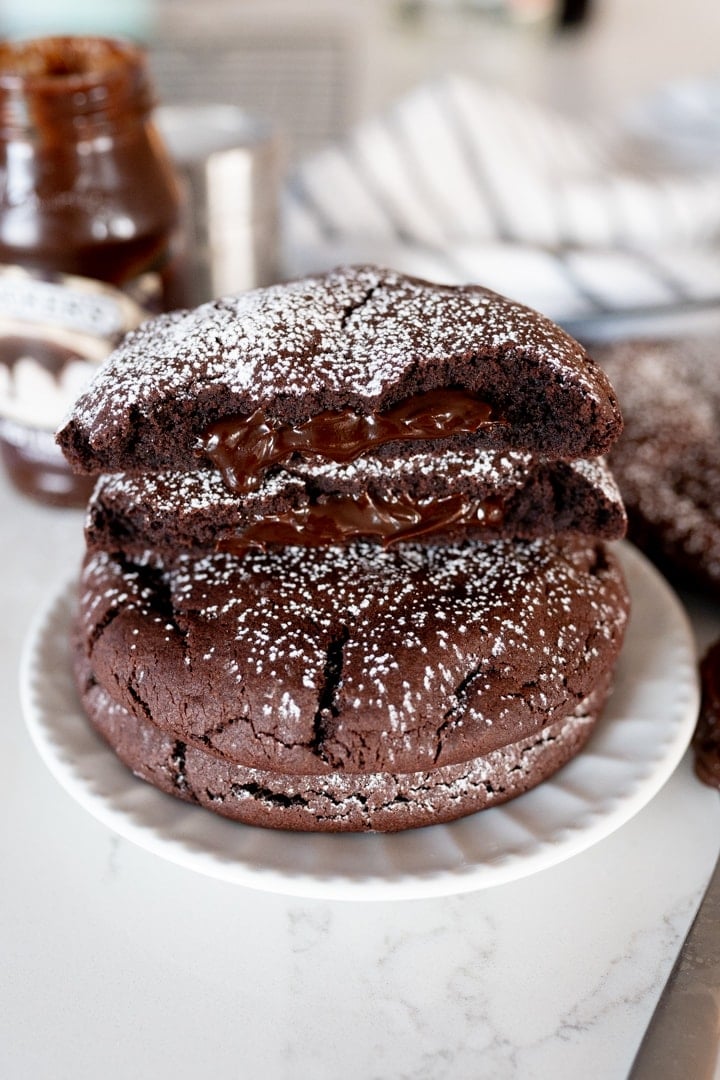 chocolate cookie with fudge in the middle, cookie broken in half with powdered sugar sprinkled on top.