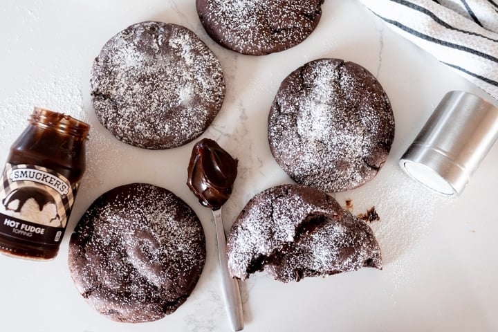 molten lava cookies on a counter with hot fudge sauce