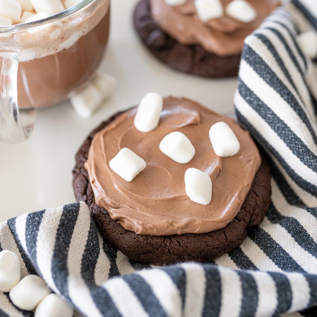 hot cocoa cookie on a striped towel next to a cup of hot cocoa