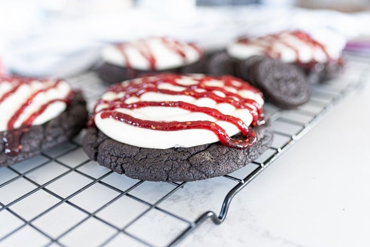 Oreo cookie with a white cheesecake frosting and a raspberry drizzle