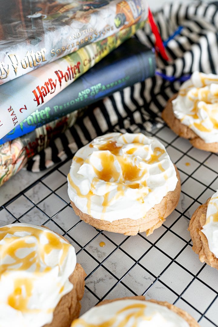 butter beer cookies with a foam frosting on a cookie cooling rack next to Harry Potter books