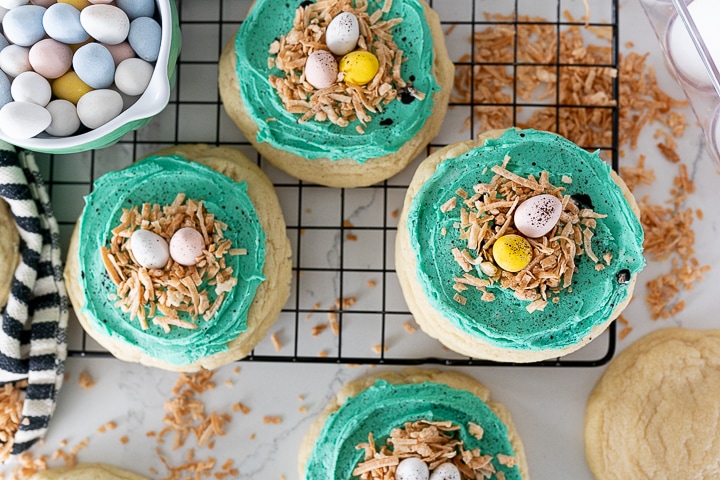 4 easter cookies on the counter and cooling rack, with robins egg frosting and coconut birds nests