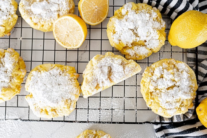 lemon cookies on a cooling rack with powdered sugar and lemons