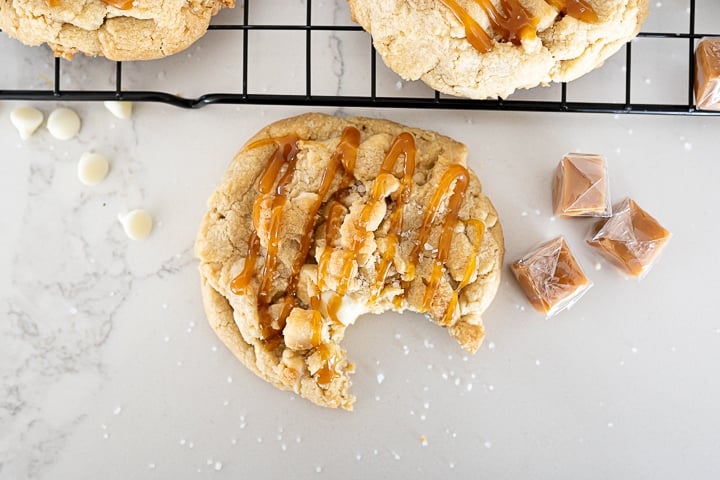 macadamia nut cookie on the counter with white chocolate, caramel and sea salt.