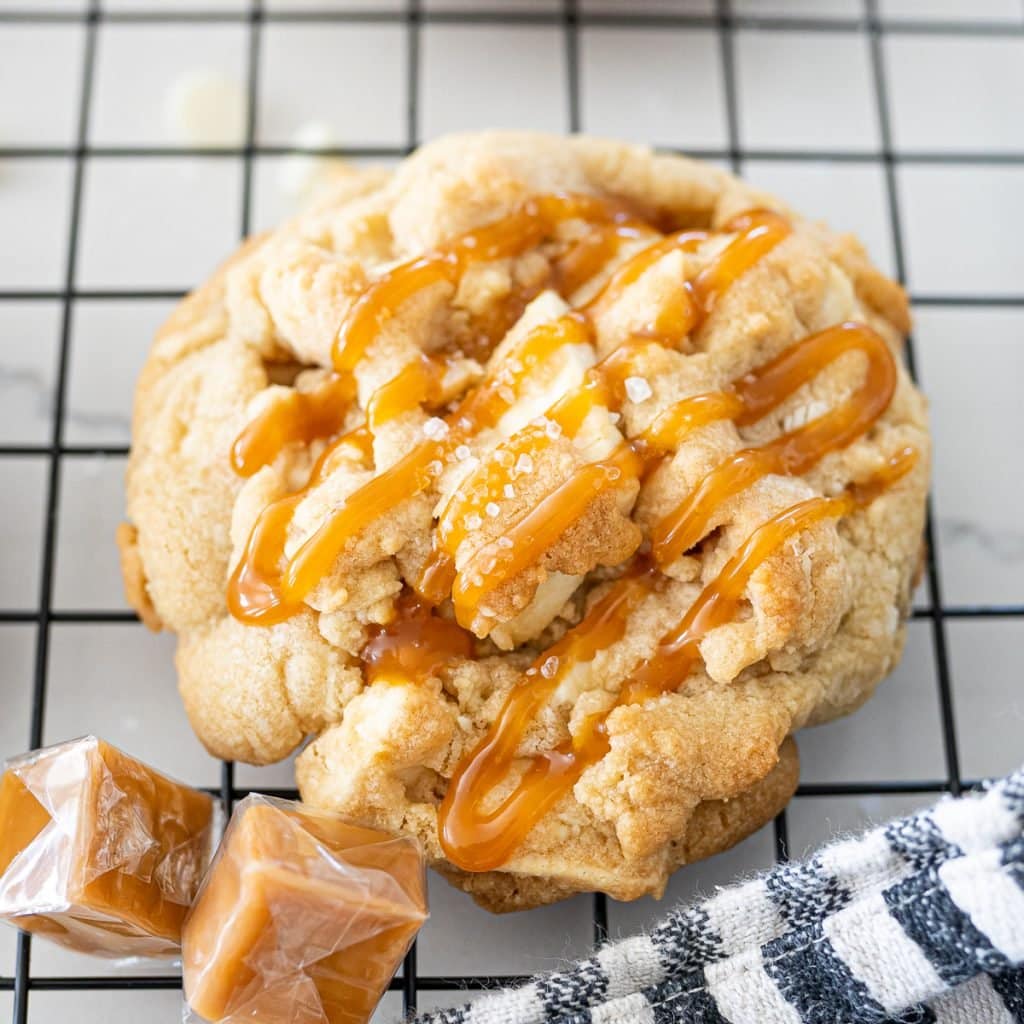 macadamia nut cookie on cookie cooling rack with white chocolate and salted caramel