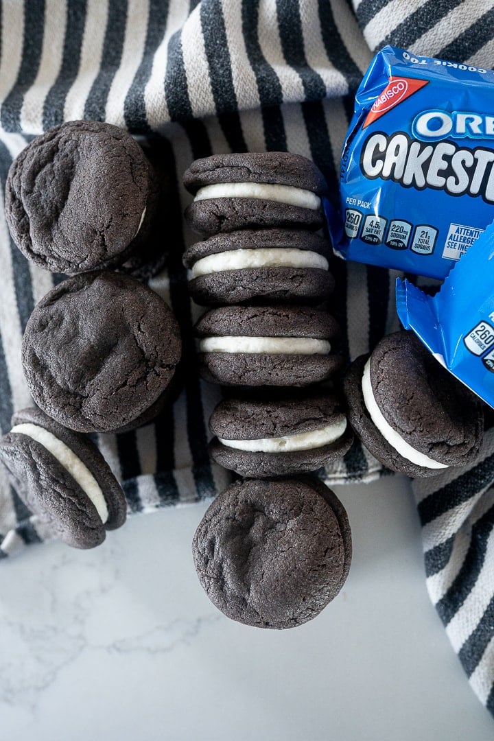 homemade oreo cakesters on the counter with a striped dishtowel stacked together.