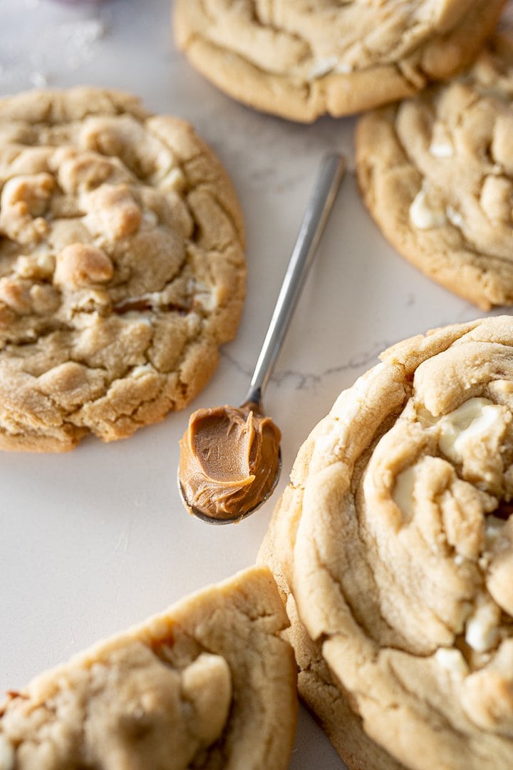 cookie butter on a spoon next to white chocolate Biscoff cookies