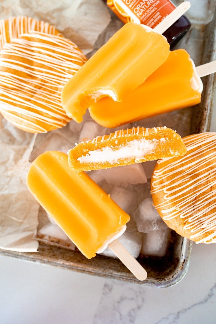 orange creamsicle cookie cut in half on a tray with popsicles