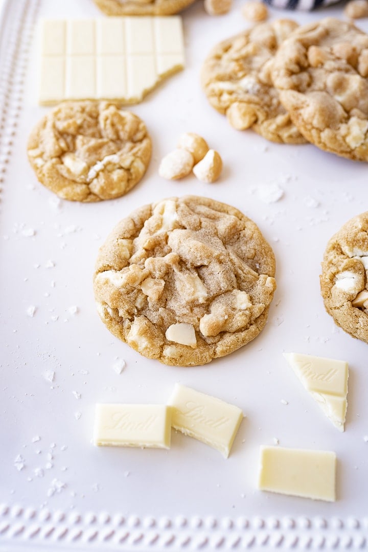 white chocolate macadamia nut cookies on the counter next to some white chocolate and macadamia nuts.
