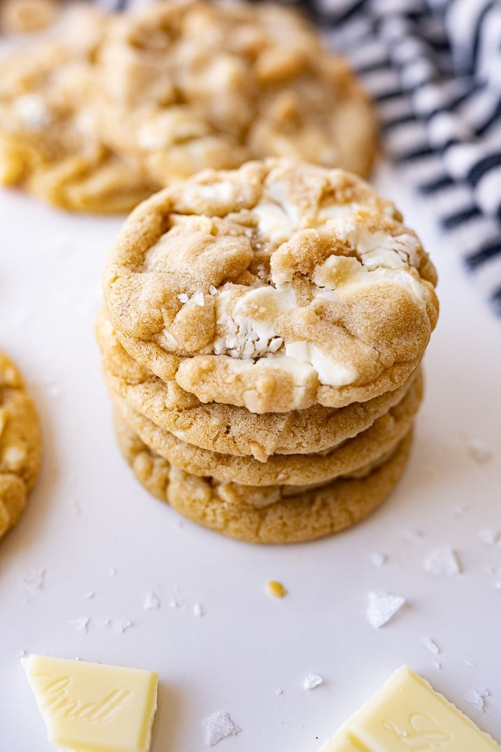 white chocolate macadamia nut cookies on the counter stacked on top of each other.