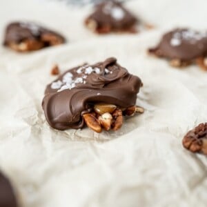 homemade chocolate turtles on parchment paper with sea salty on top.