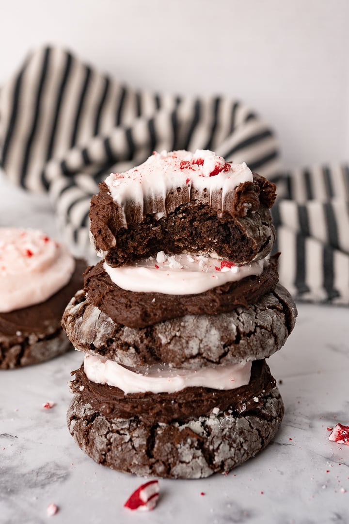 A stack of peppermint chocolate crinkle cookies with a bit taken out of the cookie on top.