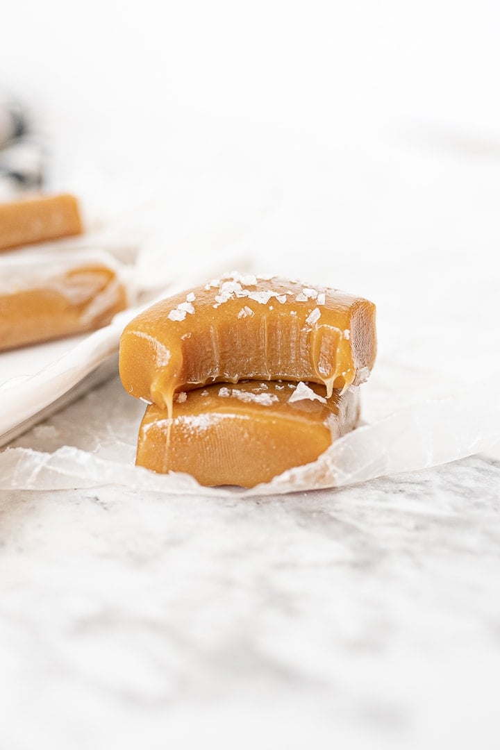 caramel squares on the counter with sea salt on top of them.