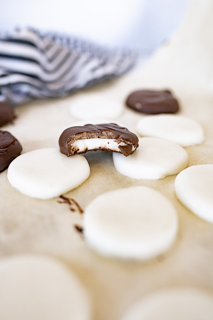 peppermint patties on parchment paper. Most without chocolate coating, but one covered with chocolate with a bite taken out.