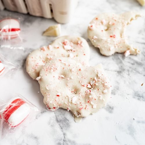 pretzel crisps dipped into white chocolate and sprinkled with peppermint on the counter.
