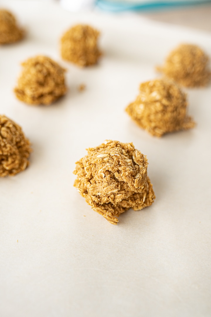 Balls of oatmeal gingersnap cookie dough on a baking sheet prior to cooking.