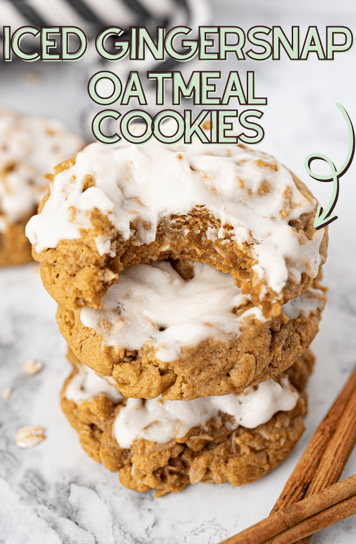A stack of iced oatmeal gingersnap cookies with a bite taken out of the top cookie and cinnamon stick on the counter. Light green writing on the photo reads "Iced gingersnap oatmeal cookies."