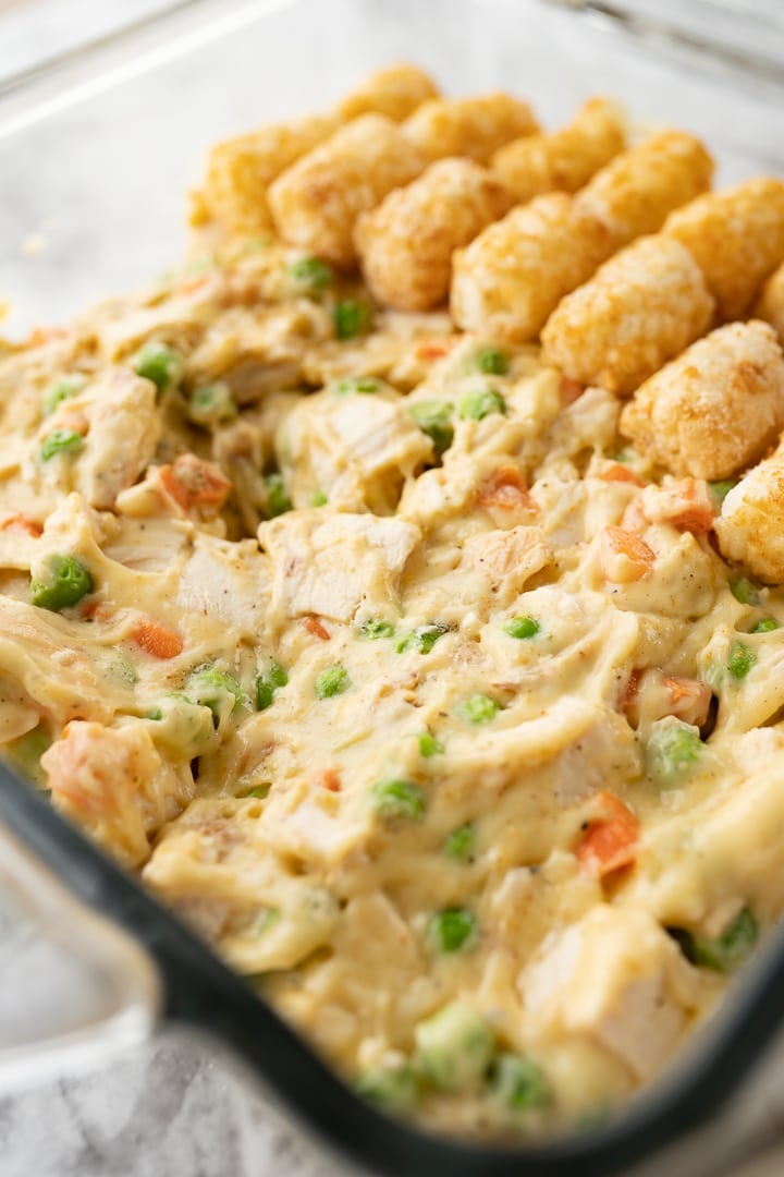 A pan of chicken tater tot casserole with tater tots only on half so you can see the casserole filling.