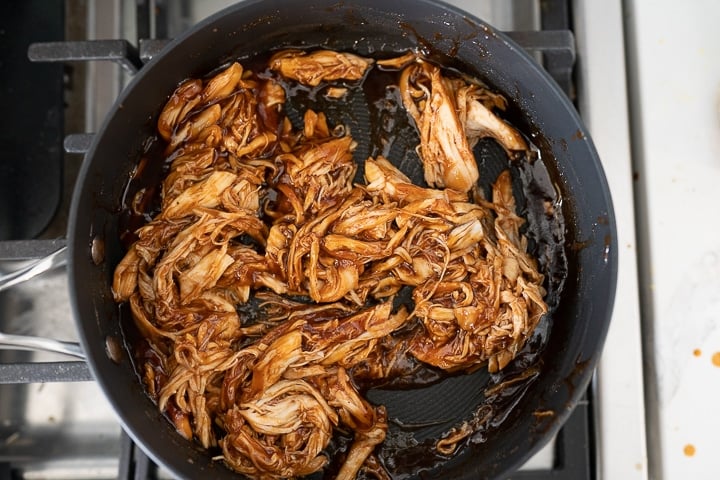 Pulled chicken in a pan on the stove.