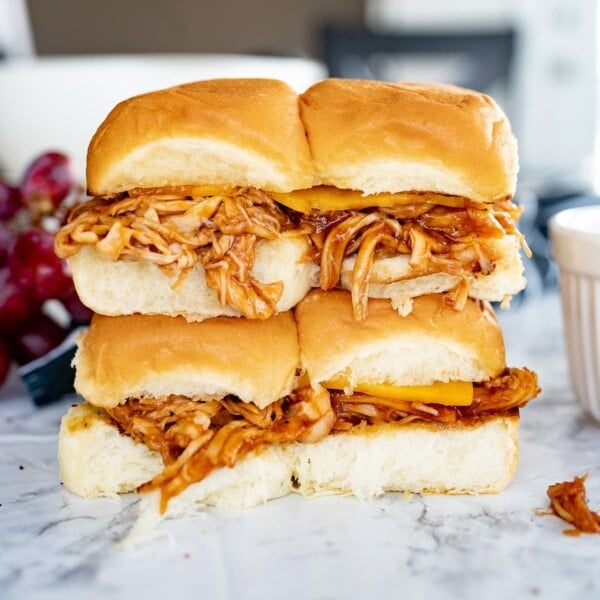 Four barbecue pulled chicken sandwiches stacked on top of each other on the counter.