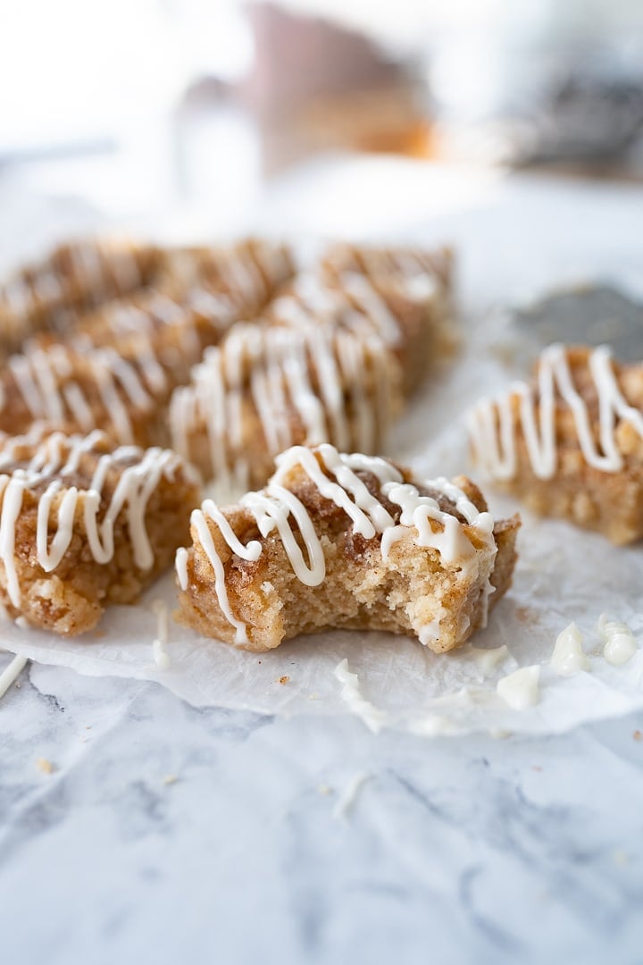Snickerdoodle bars on parchment paper on the counter with a bite taken out of one bar.