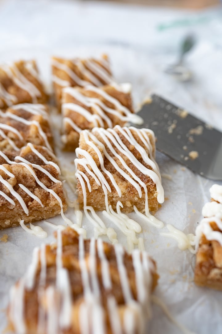 Snickerdoodle cookie bars drizzled with icing on the counter.