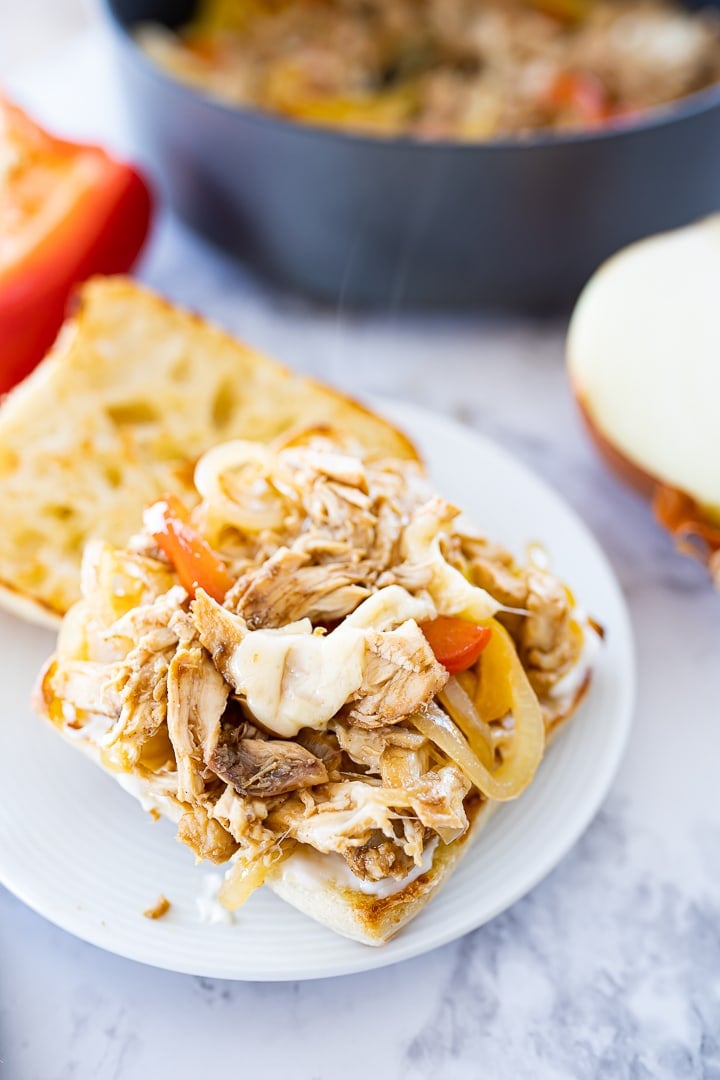 Ciabatta bread with cheesy chicken and veggies open face on a plate.